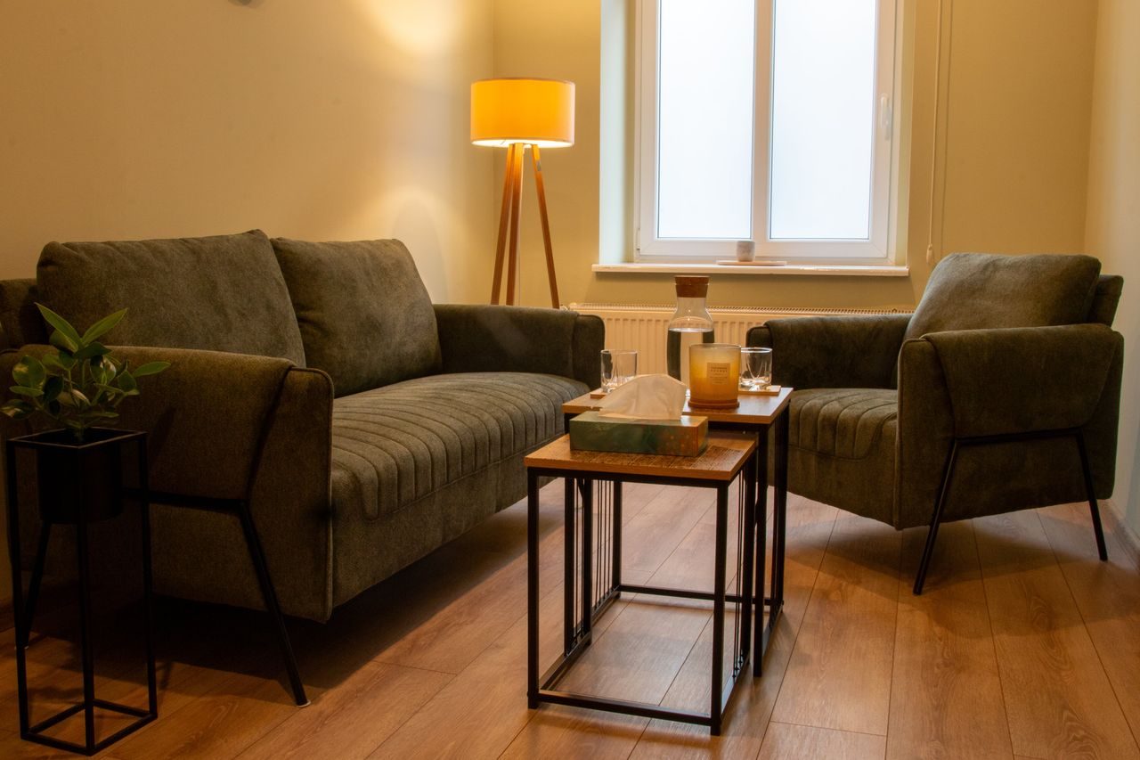 Gabinet terapeutyczny z oliwkową sofą i lampą